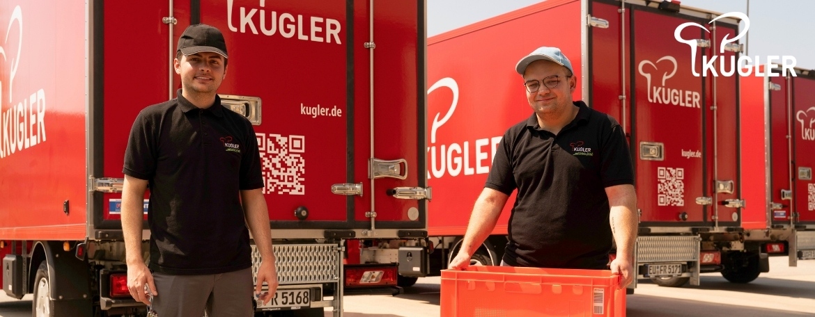 Zwei unserer Mitarbeiter mit roter E2-Kiste vor unseren roten Kugler-LKWs